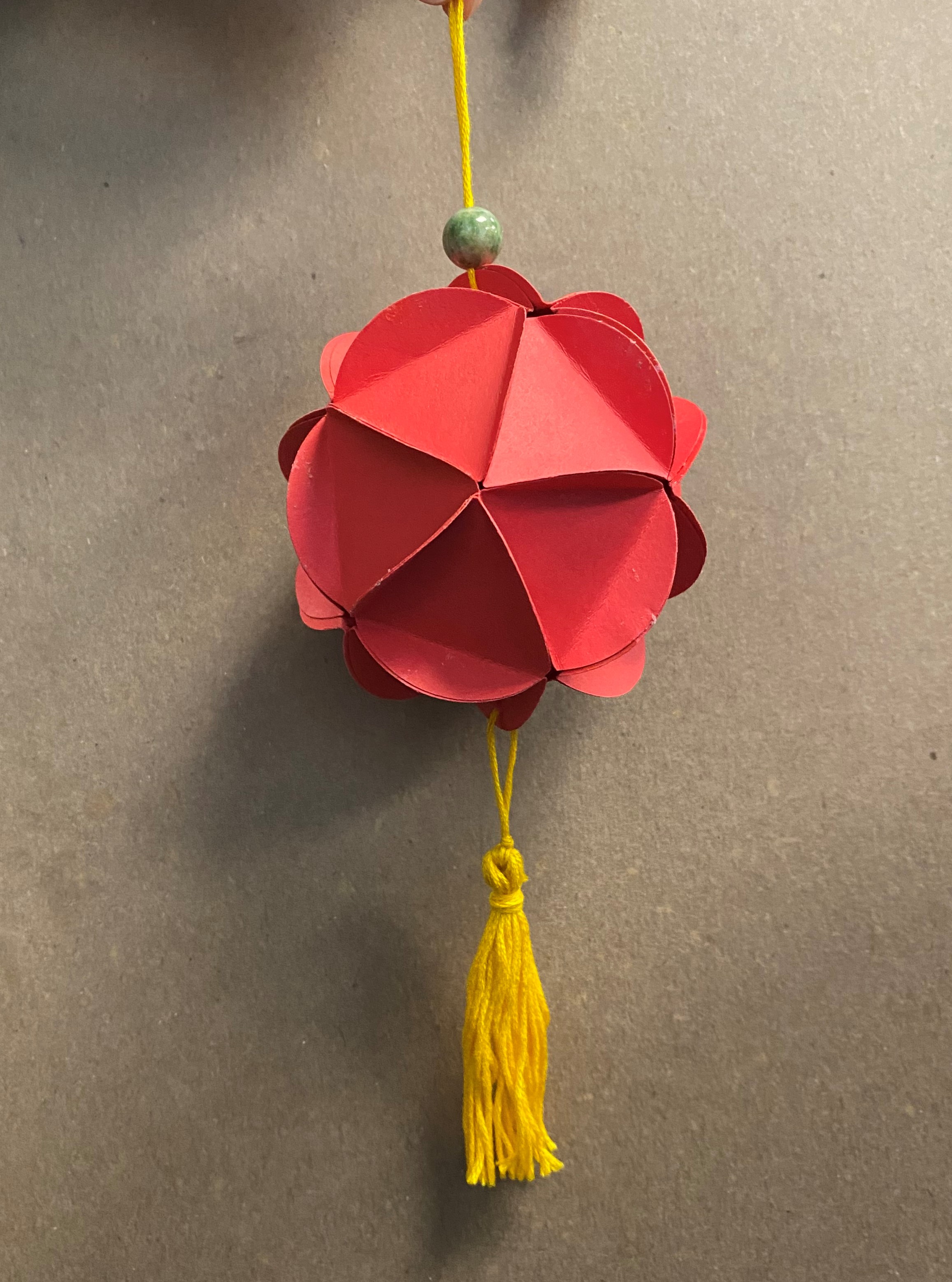 Red paper lantern with gold tassel and jade green bead
