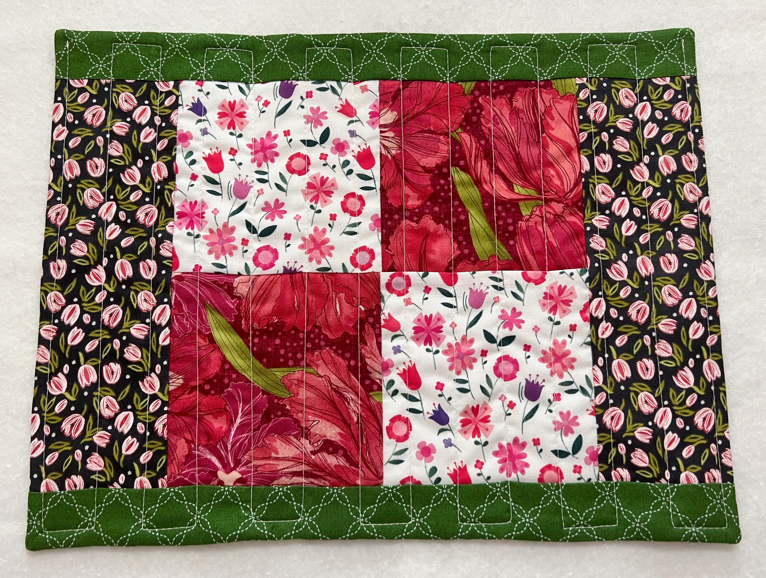 Quilted placemat in green, pink, and black floral fabrics