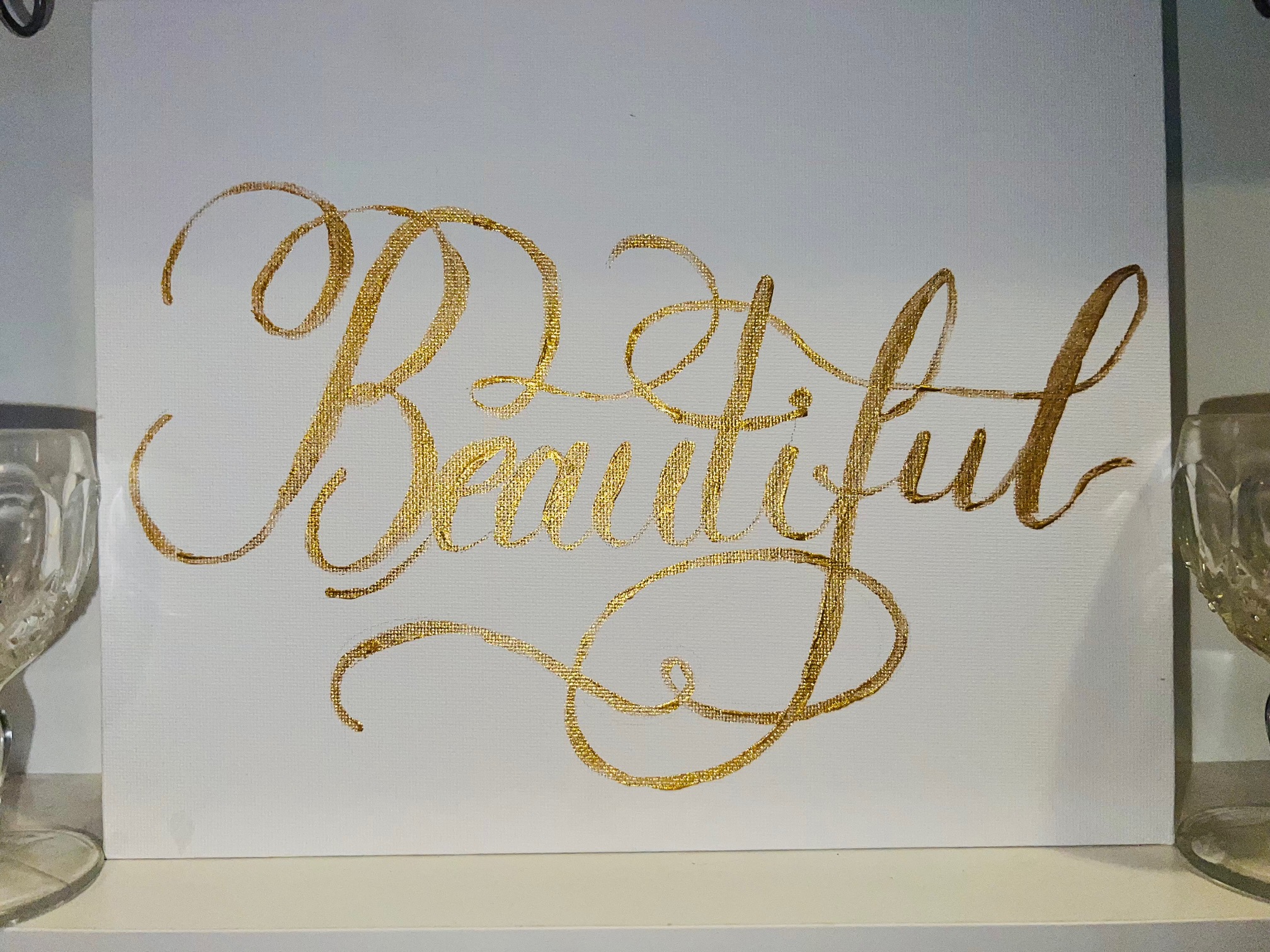 The word Beautiful painted in gold on a canvas board