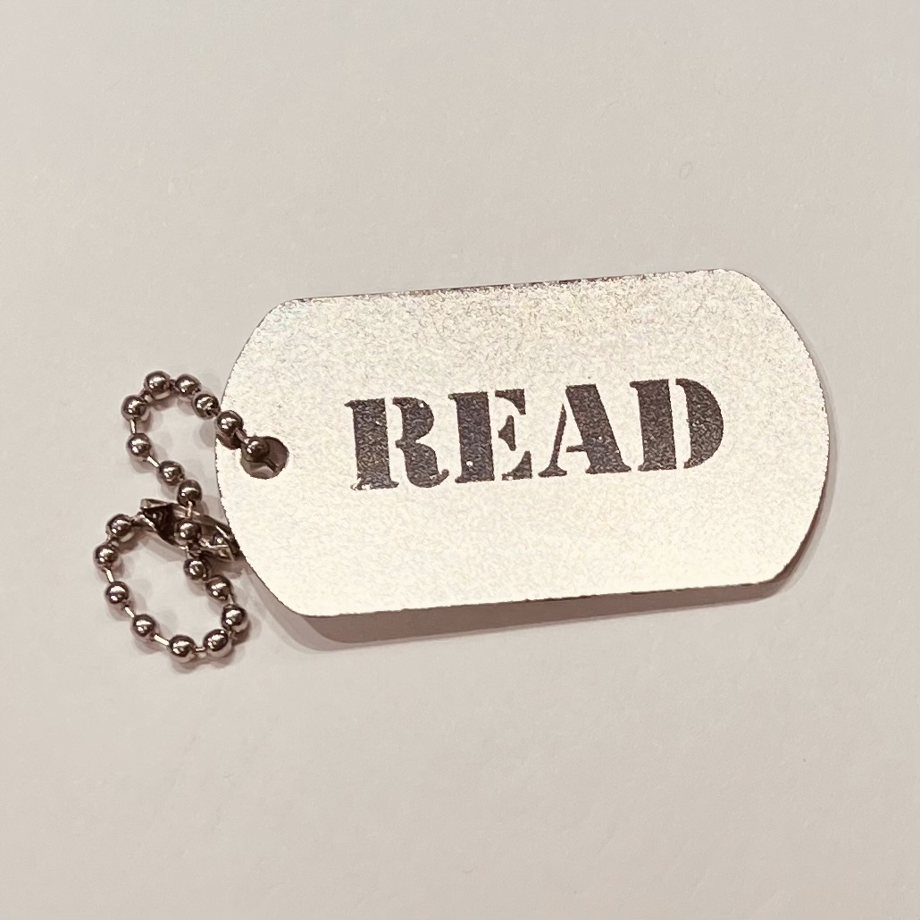 Photo of a dog tag with the word "Read"