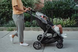 a mother pushes a child in a stroller down the sidewalk