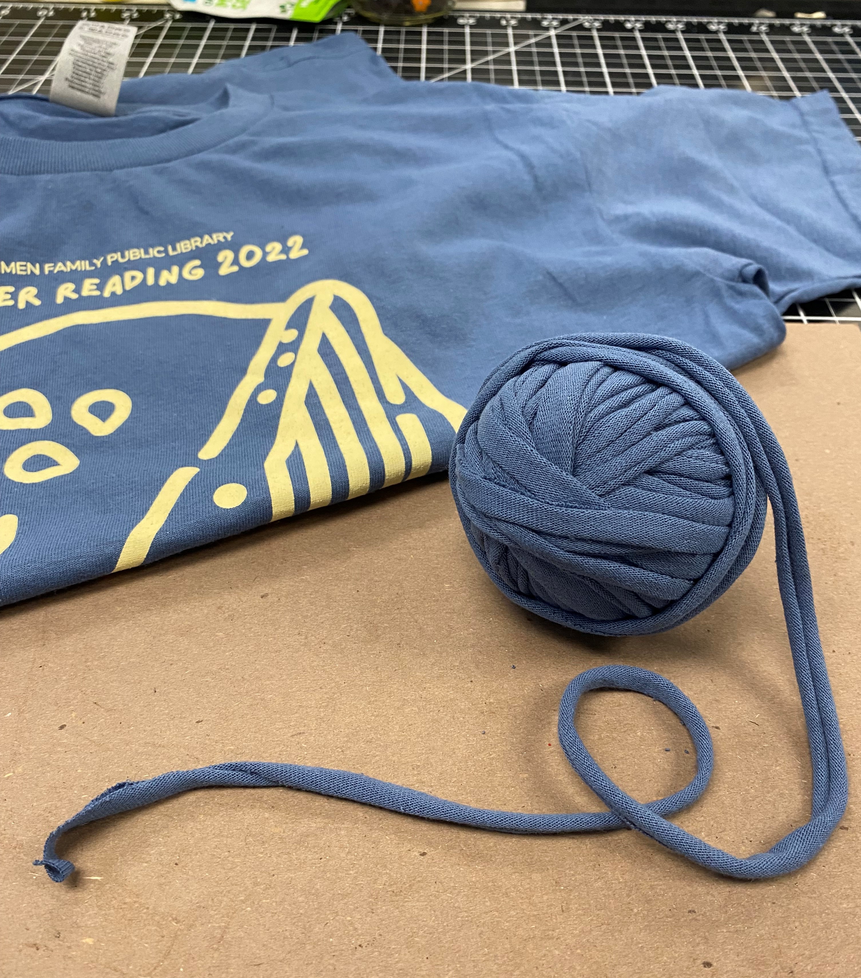 Ball of blue tshirt yarn next to a folded blue tshirt