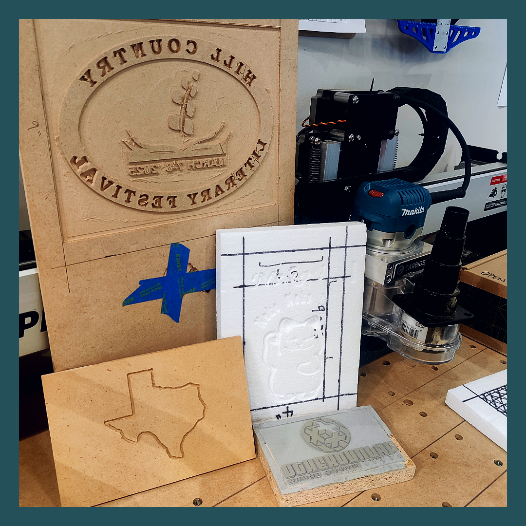 Wood cut by a router, one a cat, one the shape of Texas, one a sign for a library event