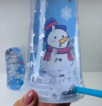 Plastic cup with paper scraps to make a snowglobe