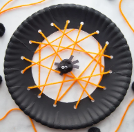 Black paper plate with yarn to create a spider web