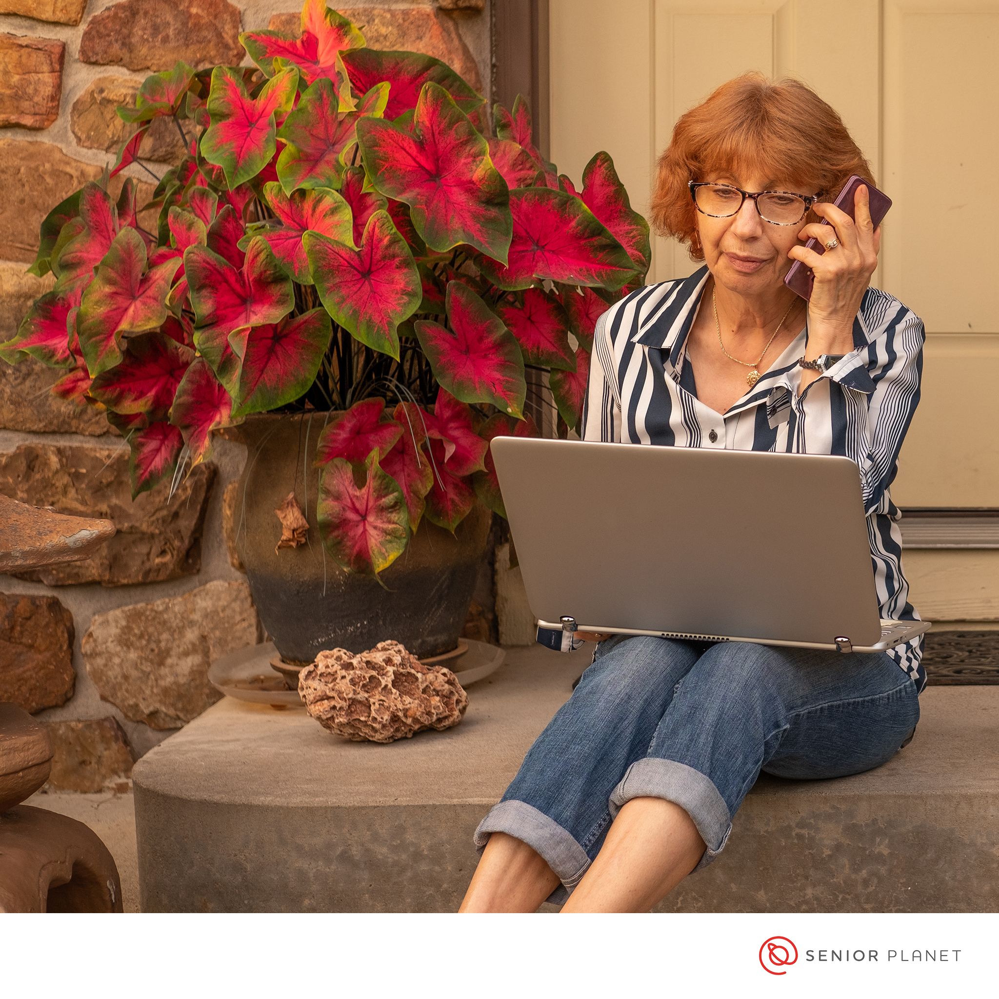 An older woman using a laptop and a smartphone