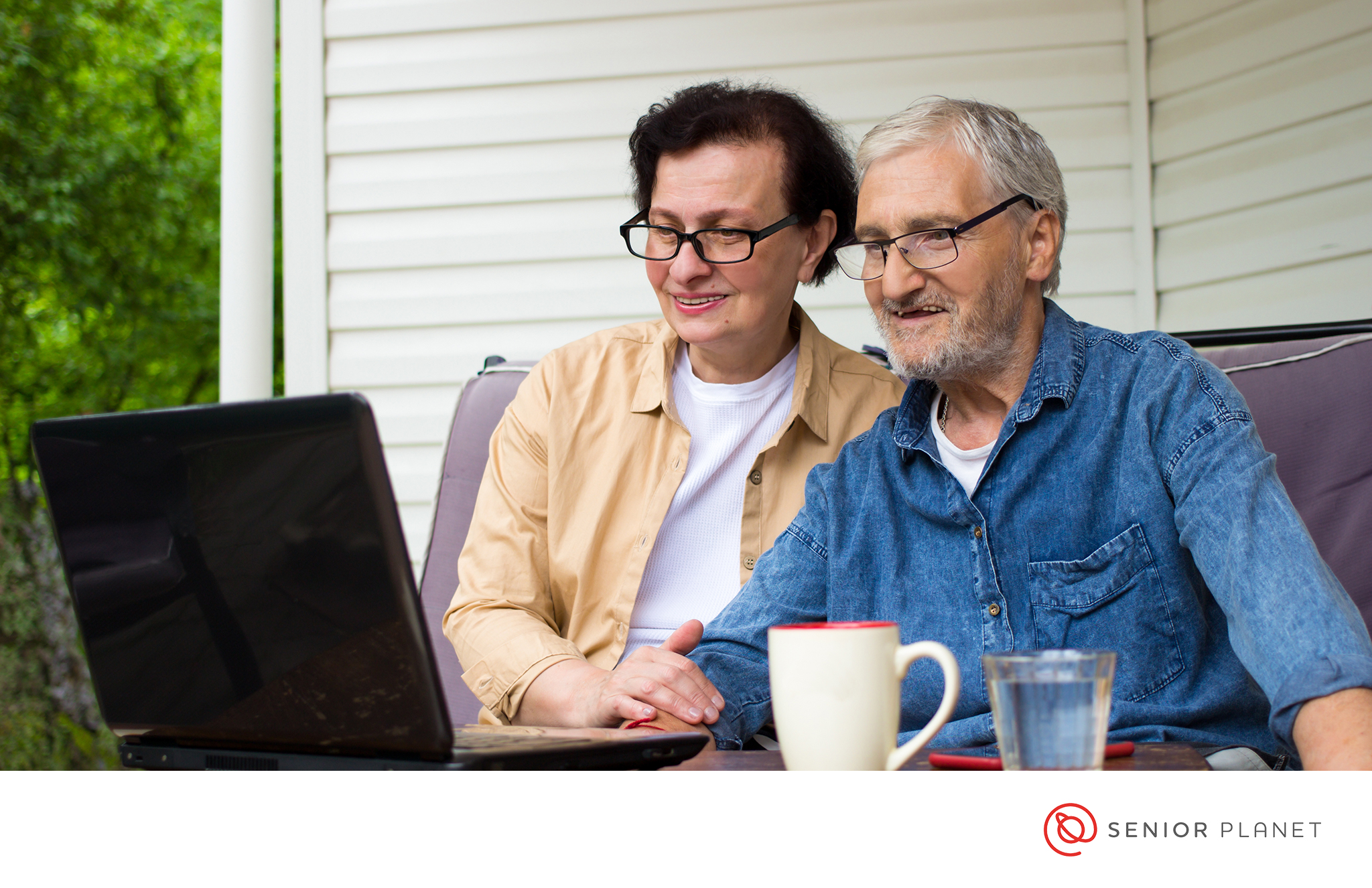 Older adults sharing a laptop and drinking coffee