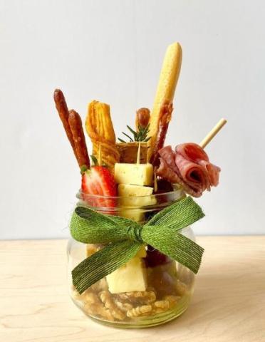 Glass jar wrapped with a green bow and filled with food items