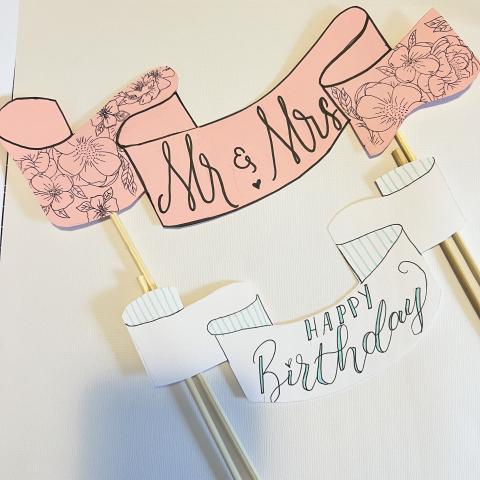 Pink cake topper with text Mr. & Mrs. and white cake topper with text Happy Birthday