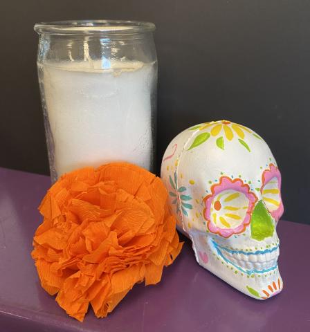 Decorative painted skull, orange paper marigold, and white candle