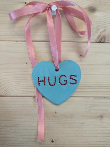 Clay painted conversation heart that says Hugs