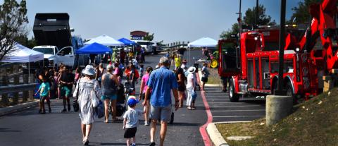 families walk through the parking lot between specialized vehicles