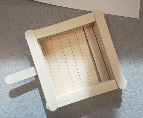 a square birdfeeder made from popsicle sticks 