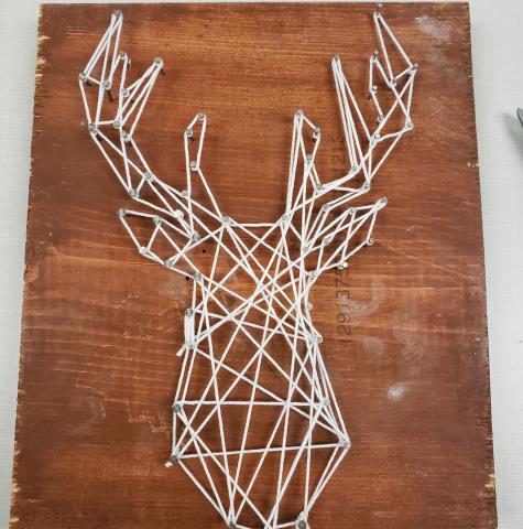String art of a deer head on a slab of wood
