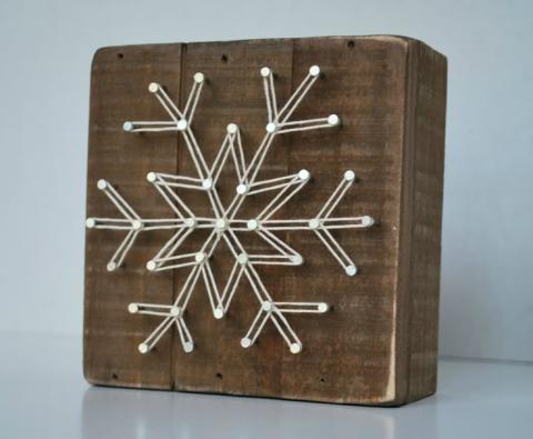 Image of geometric snowflake on a plank of wood with nails