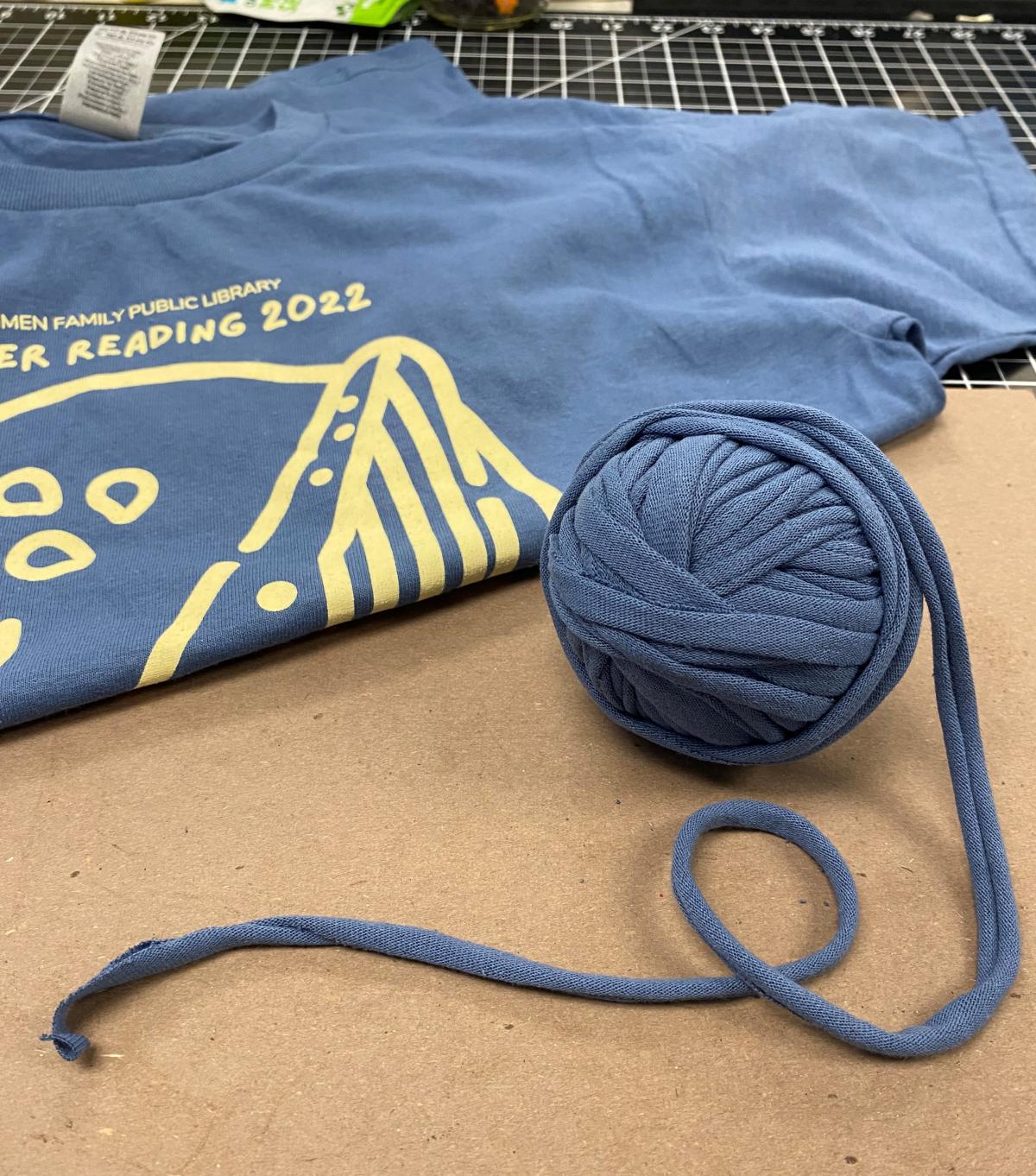 Ball of blue tshirt yarn next to a folded blue tshirt