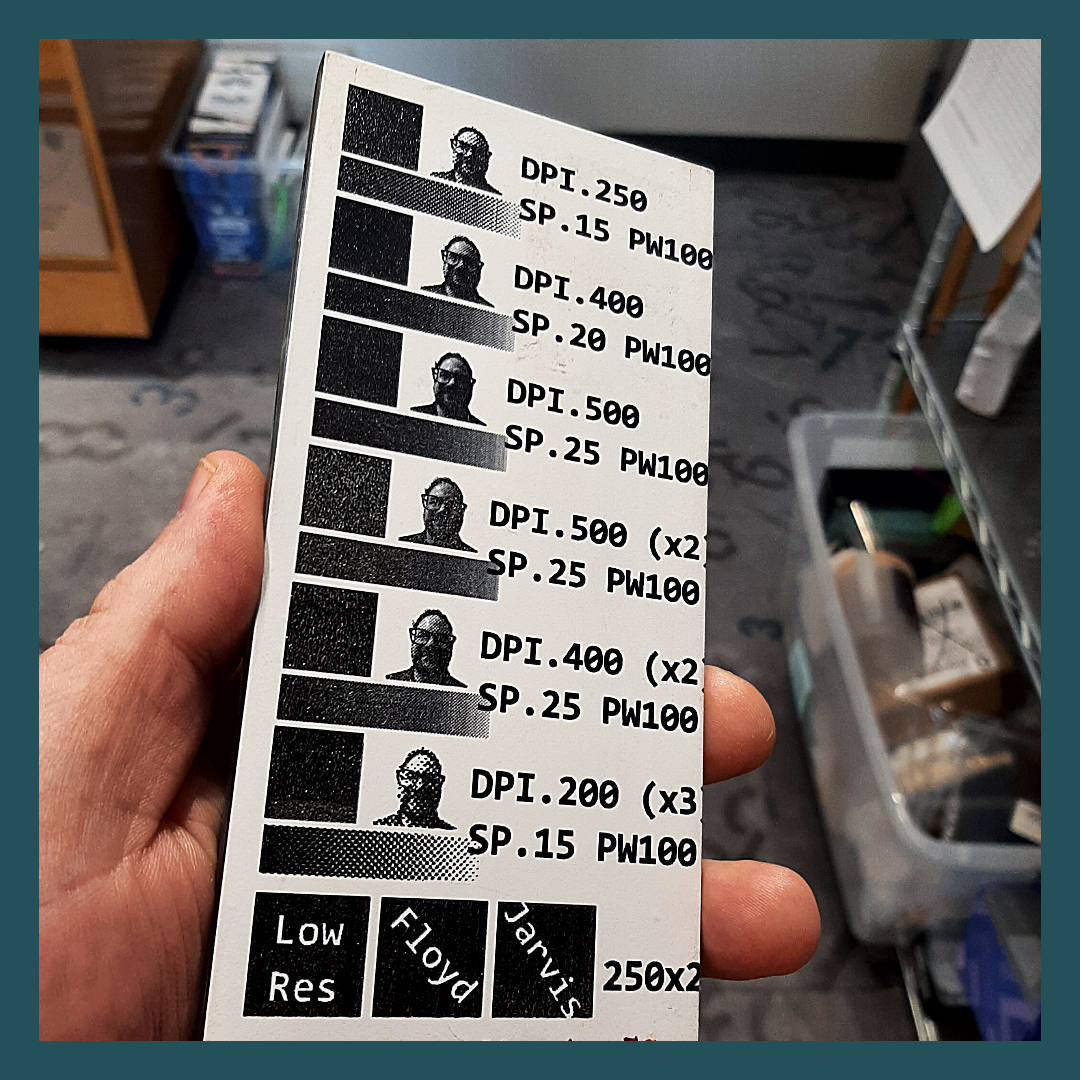 hand holding a ceramic tile that has been laser engraved with test values