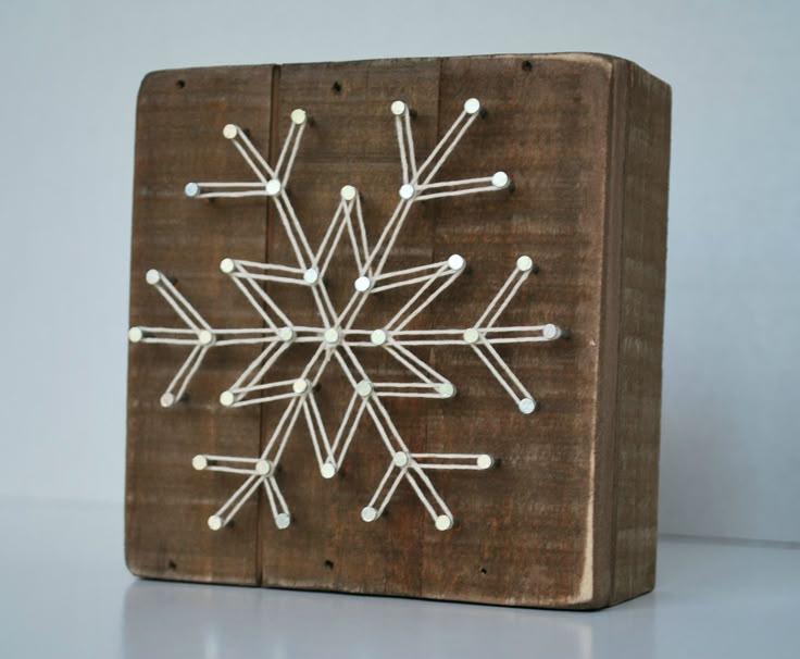 Image of geometric snowflake on a plank of wood with nails